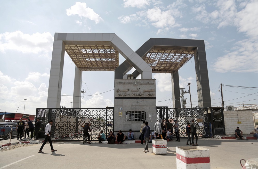 Palestinians wait to cross to the Rafah border crossing with Egypt