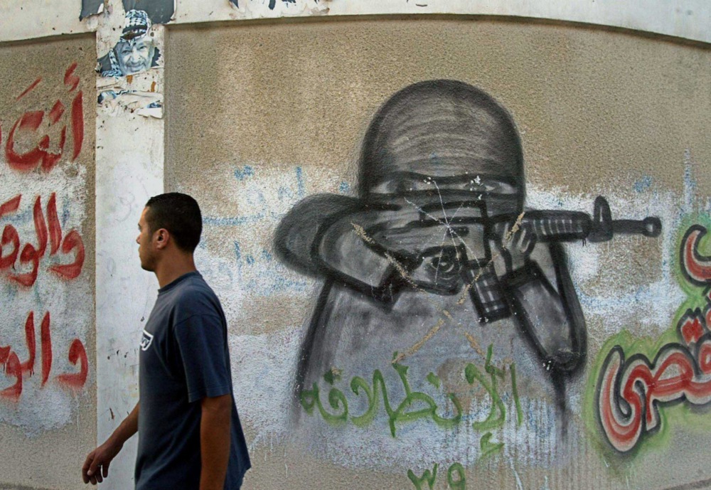 Men walks past Fatha mural