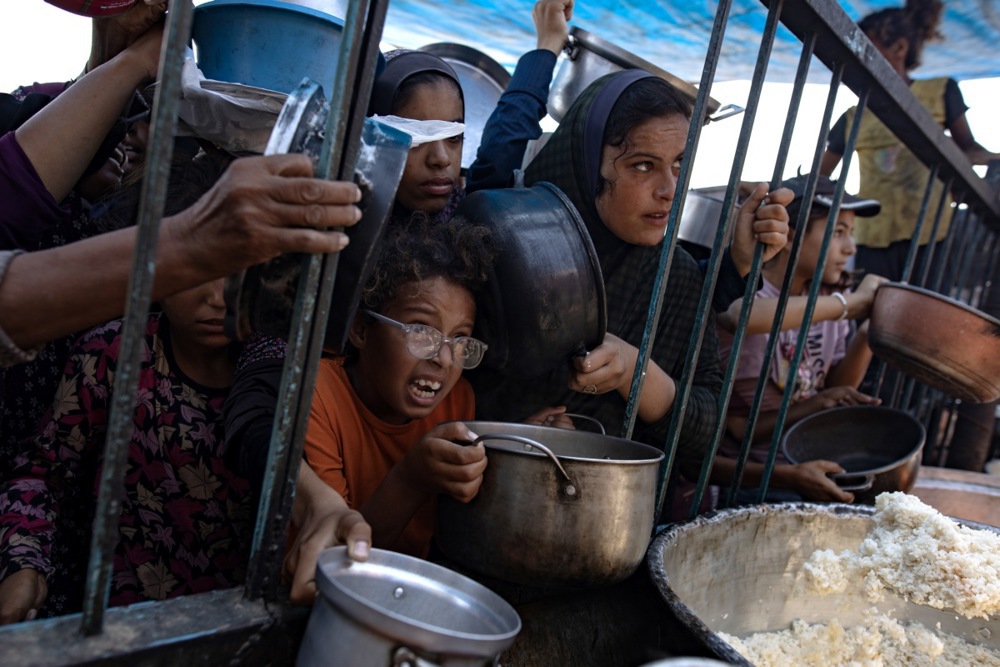 Internally displaced Palestinians collect food donated by charity in Khan Younis camp