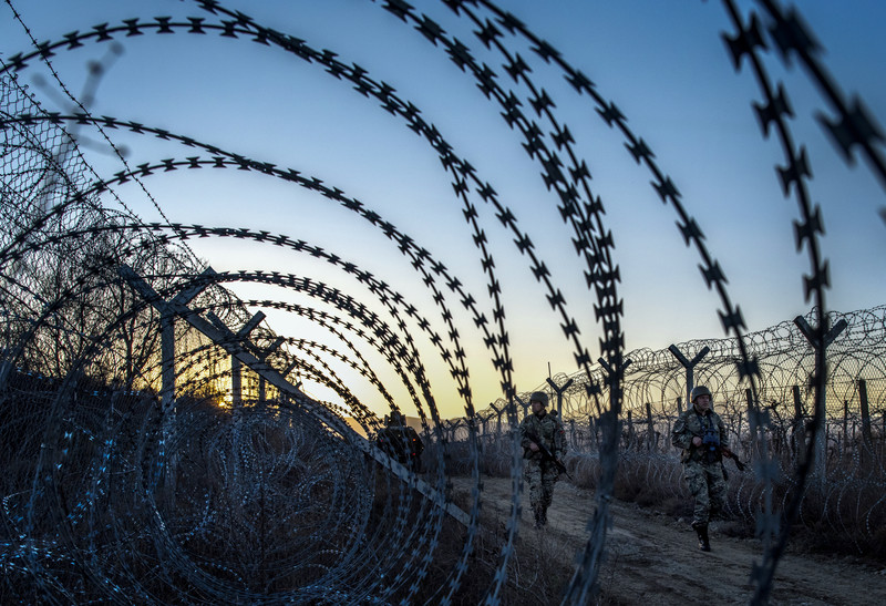 Macedonian soldiers patrol the razor wire fence at the border with Greece
