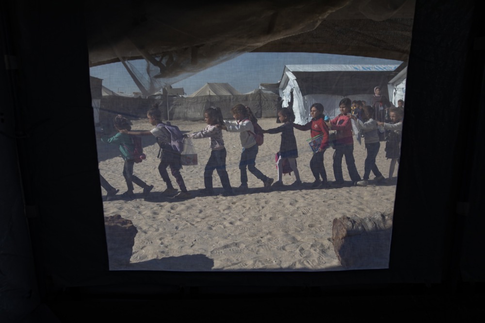 Displaced Palestinian students attend class at a tent school