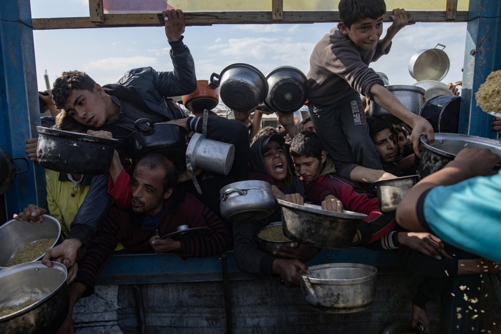 Displaced Palestinians collect donated food in Khan Yunis, southern Gaza